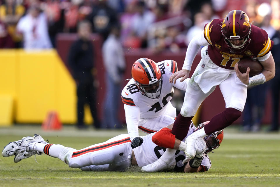 Washington Commanders quarterback Carson Wentz (11) is tacked by Cleveland Browns defensive end Chase Winovich (69) and Cleveland Browns linebacker Jermaine Carter (40) during the second half of an NFL football game, Sunday, Jan. 1, 2023, in Landover, Md. (AP Photo/Patrick Semansky)