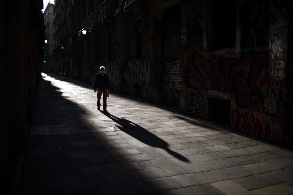 A man walks along an empty street in downtown Barcelona, Spain, Saturday, April 25, 2020 as the lockdown to combat the spread of coronavirus continues. (AP Photo/Emilio Morenatti)