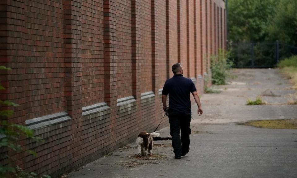 A G4S drug search dog and officer patrol the perimeter of Birmingham prison