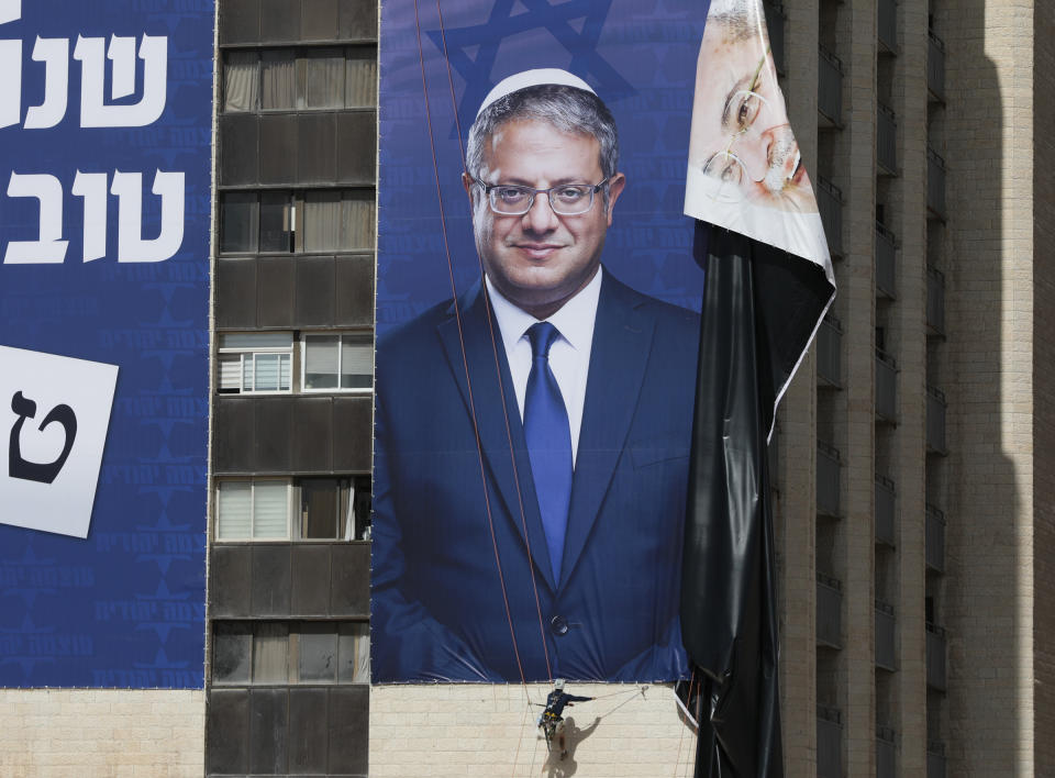 Abseiling workers hang an election billboard of Israeli far right wing Itamar Ben Gvir leader of Otzma Yehudit (Jewish power) party as they remove a billboard depicting Palestinian-Israeli politician Ahmad Tibi in Jerusalem, Sept. 29.<span class="copyright">Abir Sultan—EPA-EFE/Shutterstock</span>