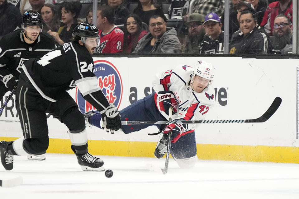 Washington Capitals left wing Beck Malenstyn, right, passes the puck past Los Angeles Kings center Phillip Danault, center, as left wing Kevin Fiala, watches during the first period of an NHL hockey game Wednesday, Nov. 29, 2023, in Los Angeles. (AP Photo/Mark J. Terrill)