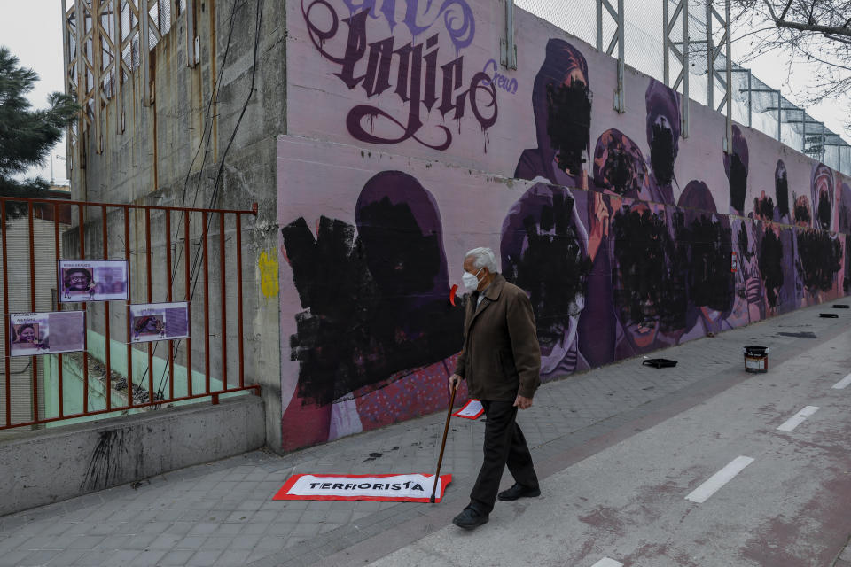 A man walks past a feminist mural vandalized during international women's day in Madrid, Spain, Monday, March 8, 2021. The original mural celebrated pioneering women such as Rosa Parks, Frida Khalo, Angela Davis, or Valentina Tereshkova among others. (AP Photo/Bernat Armangue)