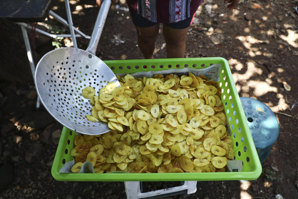 In this Oct. 10, 2019 photo, María Teresa Carballo fries plantain chips outside of her house in Santa Ana, El Salvador. Like much of Central America’s massive migration of recent years, the driving force behind the Carballo family’s exodus has been fear. Carballo lives in a neighborhood controlled by one gang, but every morning at 5 a.m. she travels to the city’s central market, which is controlled by another gang, to buy yucca, plantains and potatoes to make the fried chips she sells for a living. (AP Photo/Eduardo Verdugo)