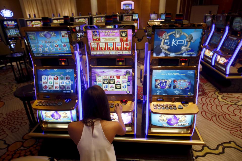 A casino trainee demonstrates how to play a slot machine at Solaire Casino in Pasay city, Metro Manila, Philippines, April 16, 2015. The Philippines has emerged as one of Asia's hottest gambling hubs after it launched its 120-hectare (1.2 square km) gaming and leisure enclave called Entertainment City in the capital, modelled on the Las Vegas strip. When paying your final respects for a relative or friend, the last thing you might expect to see at the wake is people placing bets on a card game or bingo. Not in the Philippines. Filipinos, like many Asians, love their gambling. But making wagers on games such as "sakla", the local version of Spanish tarot cards, is particularly common at wakes because the family of the deceased gets a share of the winnings to help cover funeral expenses. Authorities have sought to regulate betting but illegal games persist, with men and women, rich and poor, betting on anything from cockfighting to the Basque hard-rubber ball game of jai-alai, basketball to spider races. Many told Reuters photographer Erik De Castro that gambling is only an entertaining diversion in a country where two-fifths of the population live on $2 a day. But he found that some gamble every day. Casino security personnel told of customers begging to be banned from the premises, while a financier who lends gamblers money at high interest described the dozens of vehicles and wads of land titles given as collateral by those hoping lady luck would bring them riches. REUTERS/Erik De Castro PICTURE 13 OF 29 FOR WIDER IMAGE STORY "HIGH STAKES IN MANILA". SEARCH "BINGO ERIK" FOR ALL IMAGES.