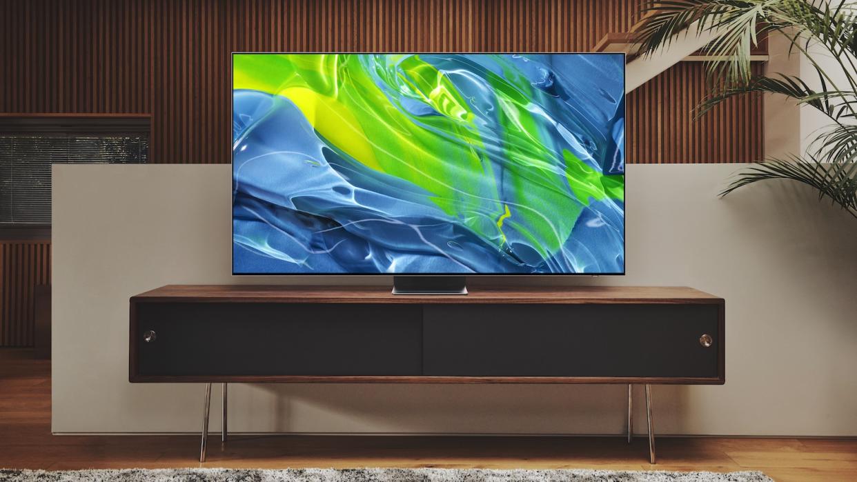  A 4K TV displaying a blue and green wave graphic, sat on a TV console. 