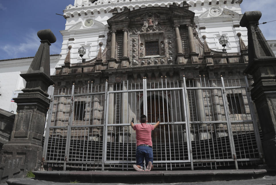 A man prays outside the closed San Francisco church on Good Friday, where there are usually crowds of penitents attending the massive "Jesus del Gran Poder" procession, during a health emergency keeping residents home to avoid getting the new coronavirus during Holy Week in Quito, Ecuador, Friday, April 10, 2020. (AP Photo/Dolores Ochoa)