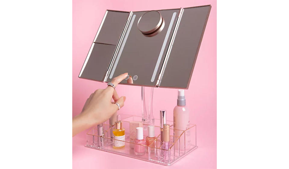 Woman touching the buttons on this tri-fold light-up vanity mirror with storage 