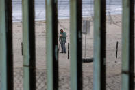 Un trabajador instala alambre de concertina en el lado estadounidense de la frontera, visto a través de las barras de la estructura fronteriza en Tijuana, México, el miércoles 14 de noviembre de 2018. (AP Foto/Gregory Bull)