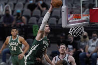 Milwaukee Bucks center Brook Lopez (11) scores over San Antonio Spurs forward DeMar DeRozan during the first half of an NBA basketball game in San Antonio, Monday, May 10, 2021. (AP Photo/Eric Gay)