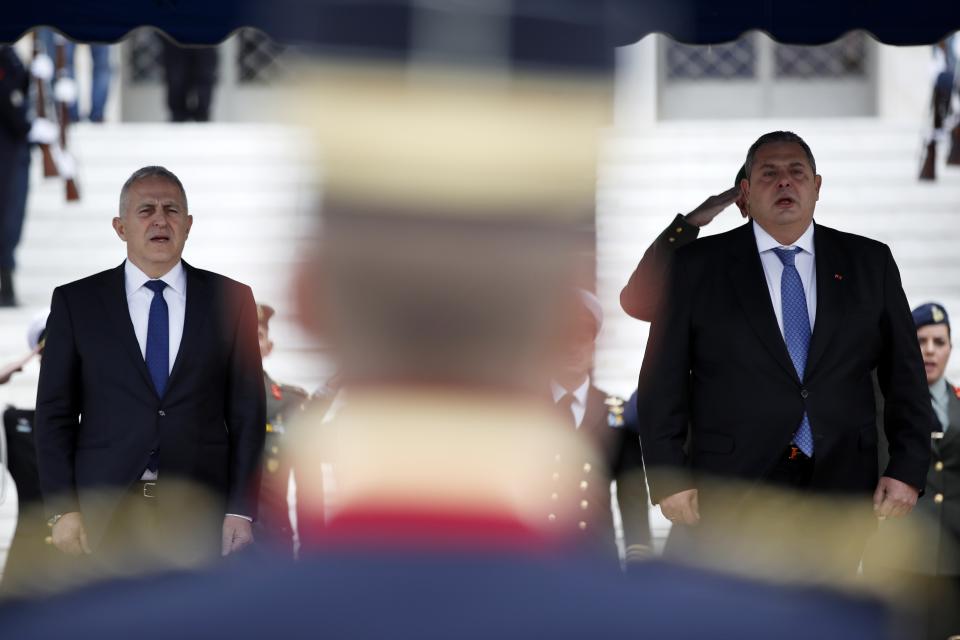 Newly appointed Defense Minister Evangelos Apostolakis, left, and outgoing Panos Kammenos, sing the national anthem during the handover ceremony in Athens, Tuesday, Jan. 15, 2019. The 62-year-old retired admiral left his post as head of the country's armed forces to replace Panos Kammenos, leader of a small nationalist party, who withdrew from the government coalition at the weekend over disagreement on a proposed deal between Greece and neighbor Macedonia. Greece's parliament has scheduled a confidence vote for late Wednesday following the collapse of Prime Minister Alexis Tsipras' governing coalition over a proposed deal to end a decades-old dispute with Macedonia. (AP Photo/Thanassis Stavrakis)