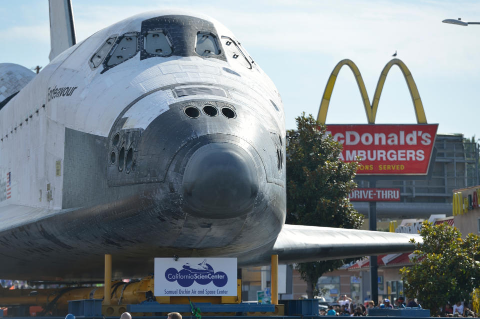 The space shuttle Endeavour travels past a fast food restaurant along on Crenshaw Blvd. enroute to the California Science Center during its final journey in Los Angeles, Calif. on Saturday, Oct. 13, 2012. (AP Photo/Jeff Gritchen, Pool)