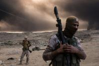 Iraqi soldiers look on as smoke rises from the Qayyarah area, some 60 kilometres (35 miles) south of Mosul