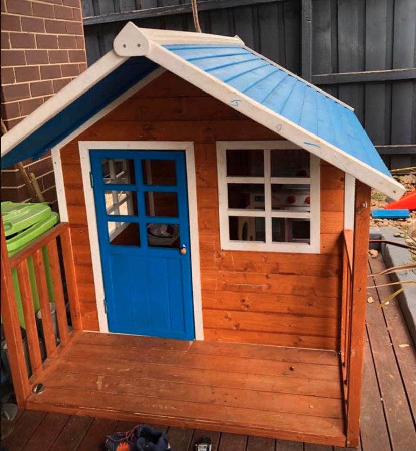 Kid's outdoor cubby playhouse with blue door and roof