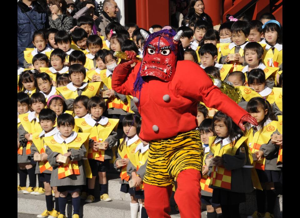 A parent of kindergarten children wearing a demon-like mask to scare pupils takes part in a bean-throwing ceremony to drive away evil and bring good luck at the annual Setsubun Festival at Tokyo's Sensoji Temple on February 3, 2011.&nbsp;