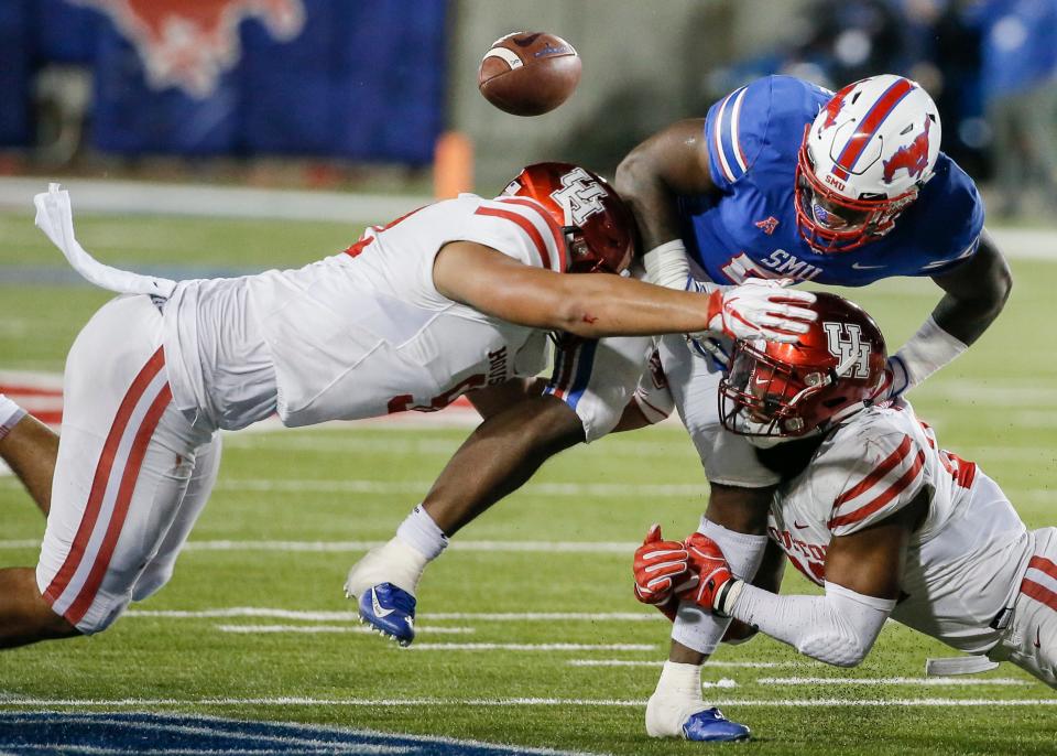 Houston linebacker Elijah Gooden, right, and defensive lineman Logan Hall, left, force SMU running back Ke'Mon Freeman (2) to fumble during the second half of an NCAA college football game Saturday, Nov. 3, 2018, in Dallas. (AP Photo/Brandon Wade)