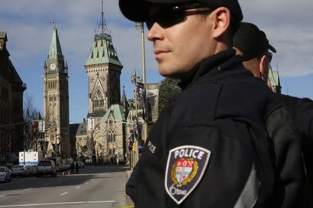 Ottawa police officers, with Parliament Hill in the background, guard the area around the National War Memorial in downtown Ottawa October 23, 2014. REUTERS/Blair Gable