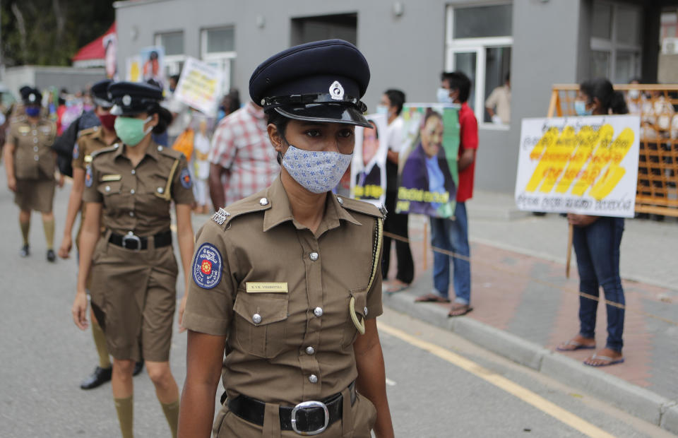 Sri Lankan women police officers guard as members of Free Women Movement hold placards demanding that government bring back all the Sri Lankan workers from the middle east as they protest outside the labor ministry in Colombo, Sri Lanka, Wednesday, July 8, 2020.(AP Photo/Eranga Jayawardena)