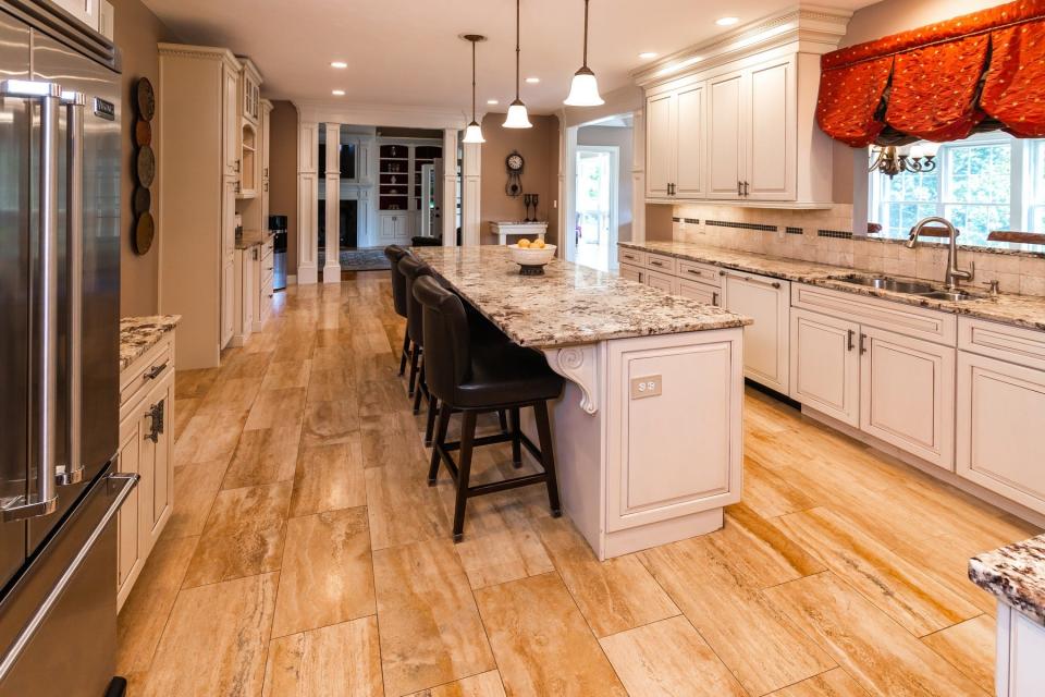 The kitchen features a Travertine marble flooring, granite countertops, maple cabinets and a center island with seating.