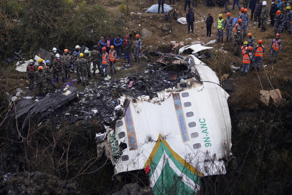 Rescuers scour the crash site in the wreckage of a passenger plane in Pokhara, Nepal, Monday, Jan.16, 2023. Nepal began a national day of mourning Monday as rescue workers resumed the search for six missing people a day after a plane to a tourist town crashed into a gorge while attempting to land at a newly opened airport, killing at least 66 of the 72 people aboard in the country's deadliest airplane accident in three decades.(AP Photo/Yunish Gurung)