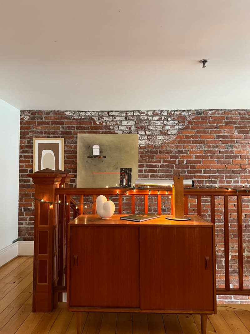 Mid-century Modern cabinet in loft bedroom with exposed brick wall.