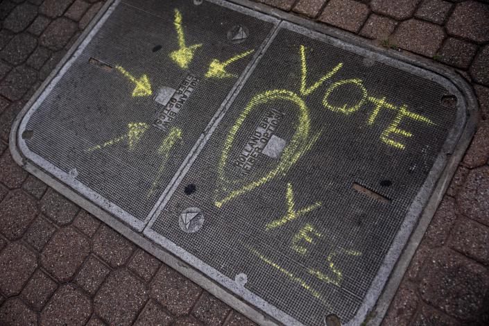 A fiber optic box sits on the sidewalks of downtown with the words 'vote yes' written in chalk Monday, Aug. 1, 2022, in downtown Holland. The bond proposal to build a fiber optic network passed during Tuesday's election.