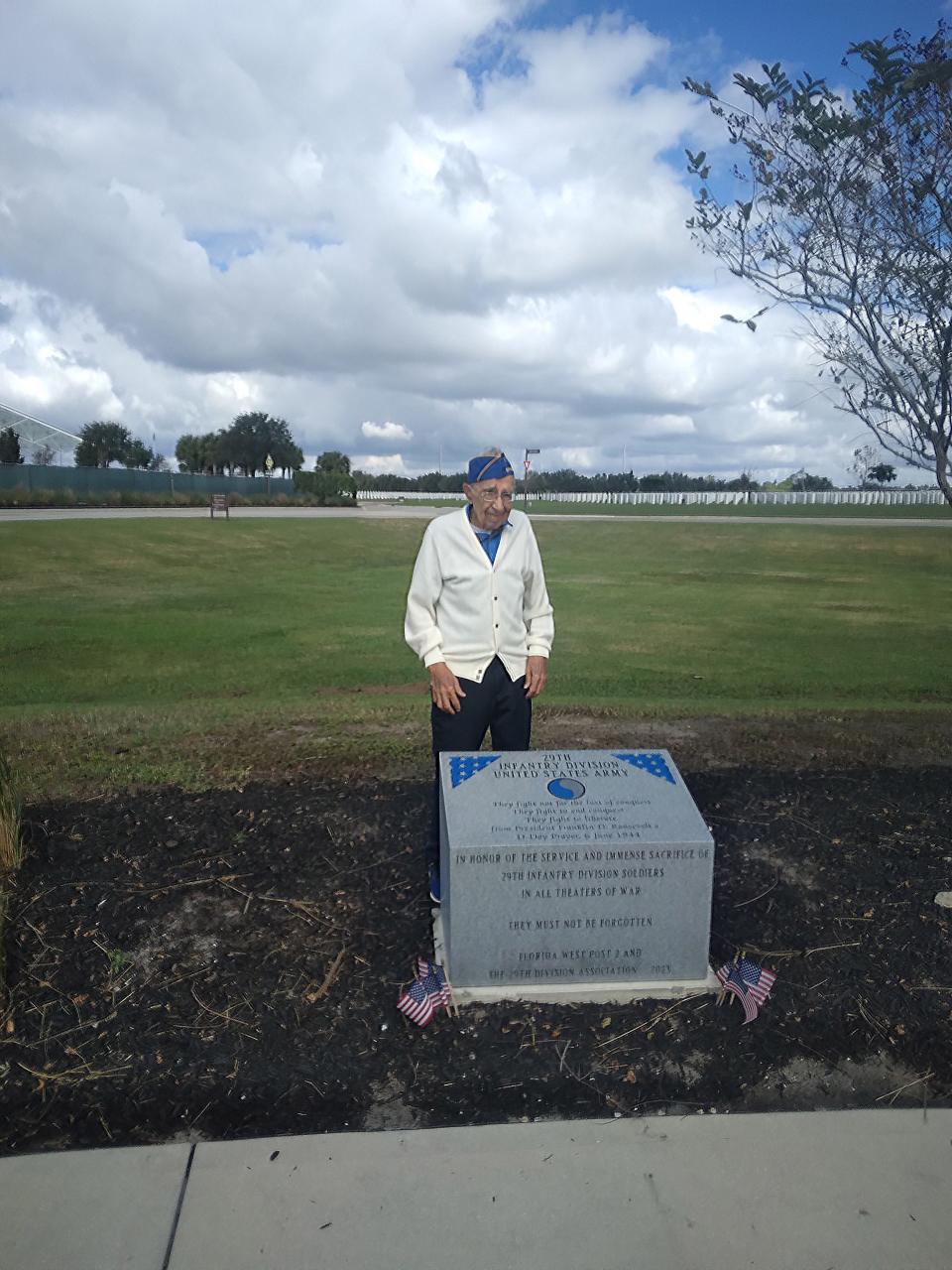 Cosmo Uttero poses by a marker at Sarasota National Cemetery for the 29th Infantry Division and sacrifices troops made during World War II.