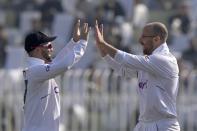 England's Jack Leach, center, celebrates with Ben Duckett after taking the wicket of Pakistan's Imam-ul-Haq during the third day of the first test cricket match between Pakistan and England, in Rawalpindi, Pakistan, Saturday, Dec. 3, 2022. (AP Photo/Anjum Naveed)