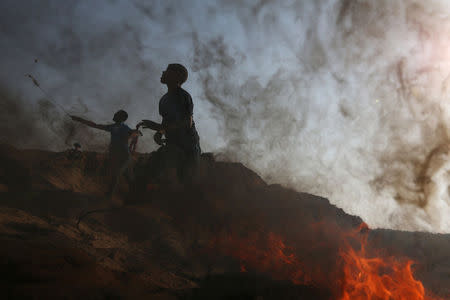 Palestinian protesters hurl stones towards Israeli troops during clashes near the border between Israel and central Gaza Strip July 21, 2017. REUTERS/Ibraheem Abu Mustafa