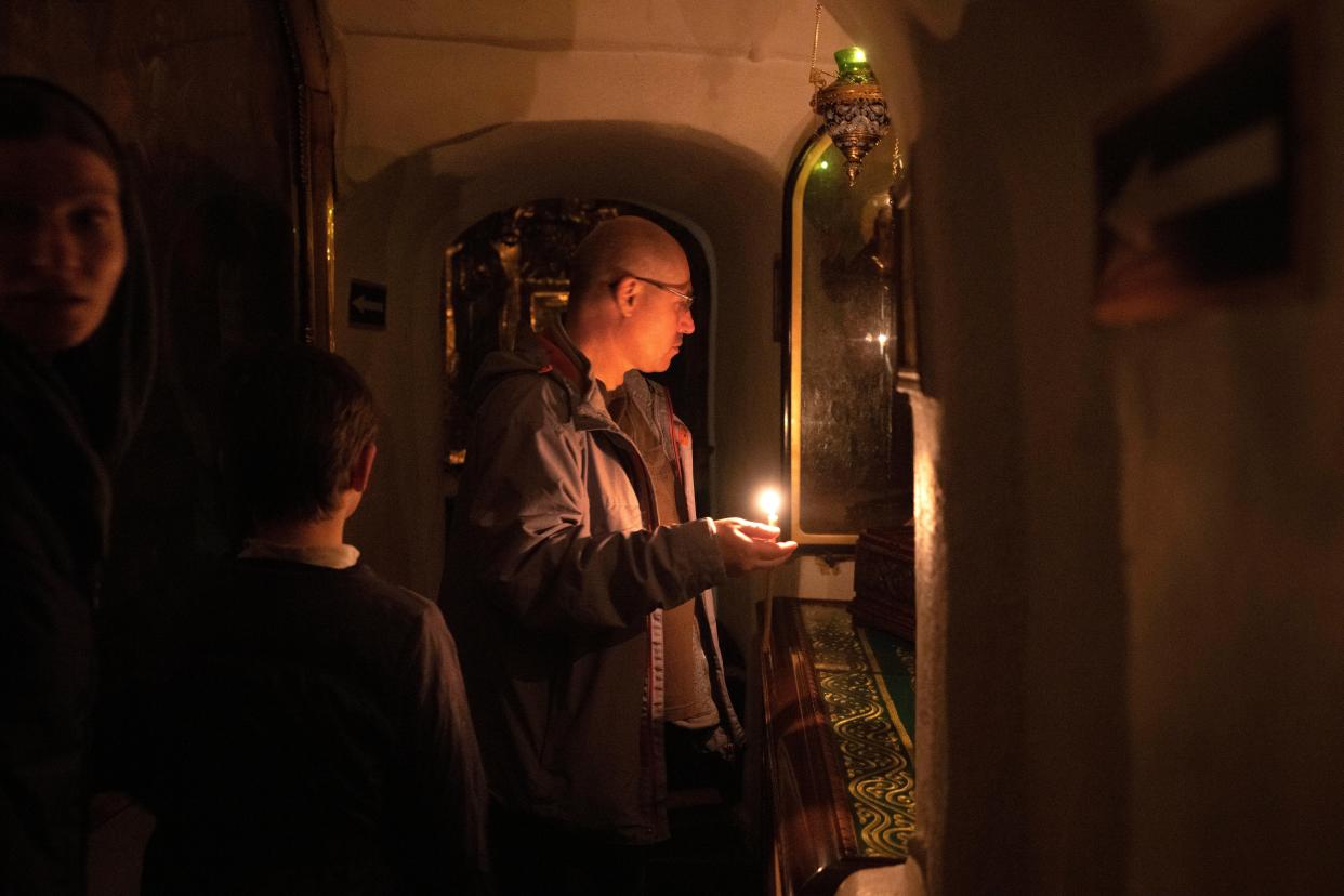 People pray at a sarcophagus with a holy relic in the underground labyrinth of the Monastery of the Caves (Copyright 2023 The Associated Press. All rights reserved)