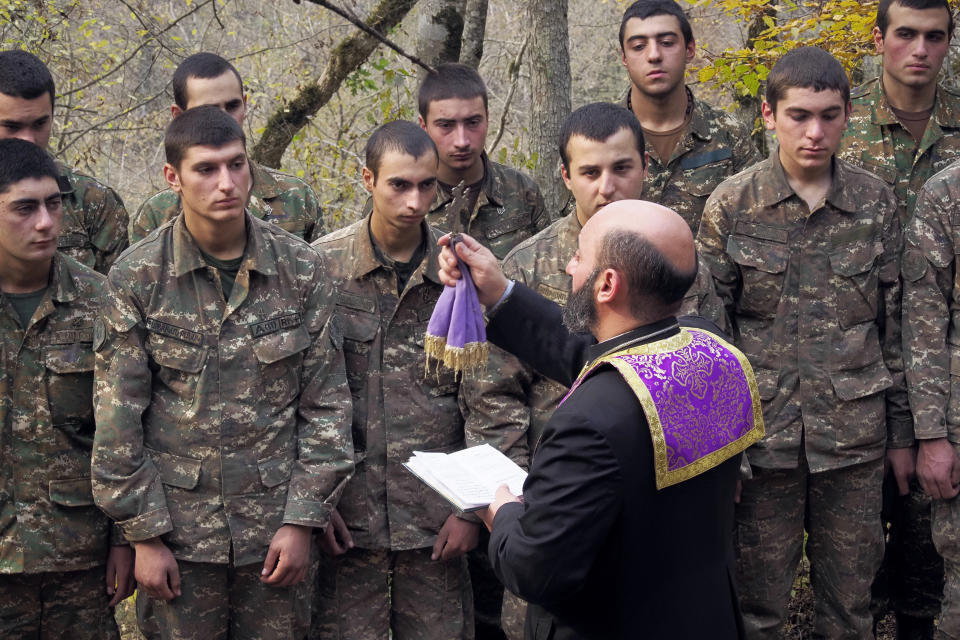 Priest Aristakes Hovhannisyan conducts a baptism ceremony for ethnic Armenian soldiers in a military camp near the front line during a military conflict in separatist region of Nagorno-Karabakh, Monday, Nov. 2, 2020. Fighting over the separatist territory of Nagorno-Karabakh entered sixth week on Sunday, with Armenian and Azerbaijani forces blaming each other for new attacks. (AP Photo)