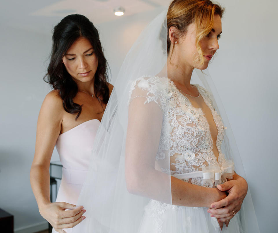 A bridesmaid puts on a bride's veil before the wedding