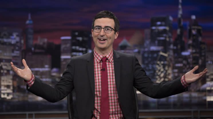 John Oliver in a red plaid shirt and red tie