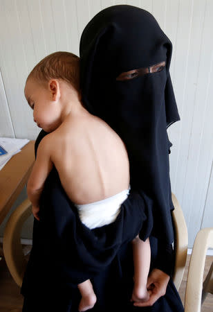 FILE PHOTO: Chechen woman Laila Magomedovna Gazieva, the widow of an Islamic State militant, holds her son Obaida at Hammam Al-Alil camp south of Mosul, Iraq, September 13, 2017. REUTERS/Azad Lashkari/File Photo