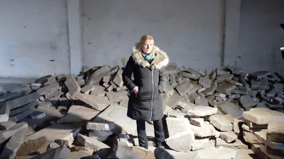 Debra Brunner of The Together Plan stands in a warehouse in Brest, surrounded by the broken headstones. - The Together Plan