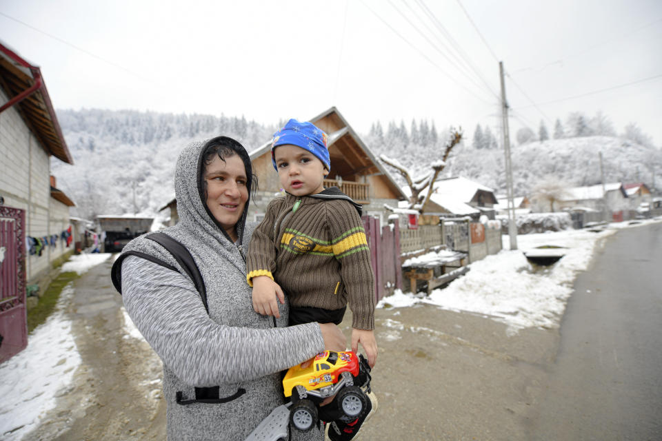 A woman holds a child while watches Valeriu Nicolae distributes boxes containing basic food, hygiene and medicinal products in Leresti, Romania, Saturday, Jan. 9, 2021. The rights activist has earned praise for his tireless campaign to change for the better the lives of the Balkan country’s poorest and underprivileged residents, particularly the children. (AP Photo/Andreea Alexandru)