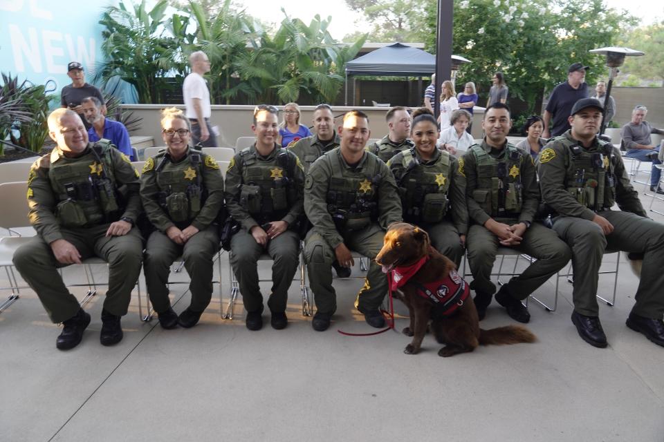 Members of the Sheriff's Department take a photo with Huntington Beach Fire Department Peer Support Dog, Kingman, as they join the Trabuco Caynon community join in a prayer vigil to help families cope with the Cook's Corner shooting tragedy at the Saddleback Church in Lake Forest, Calif., Friday, Aug. 25, 2023. (AP Photo/Damian Dovarganes)