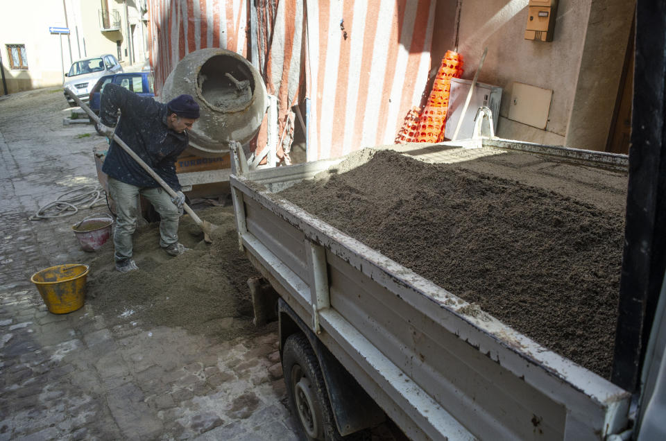 This image provided by Cain Burdeau shows a construction worker mixing concrete on a street in Castelbuono, Sicily, Italy. In Italy, masonry using concrete is an inescapable aspect of construction and a crucial difference between home building in North America and in Europe. (Cain Burdeau via AP)