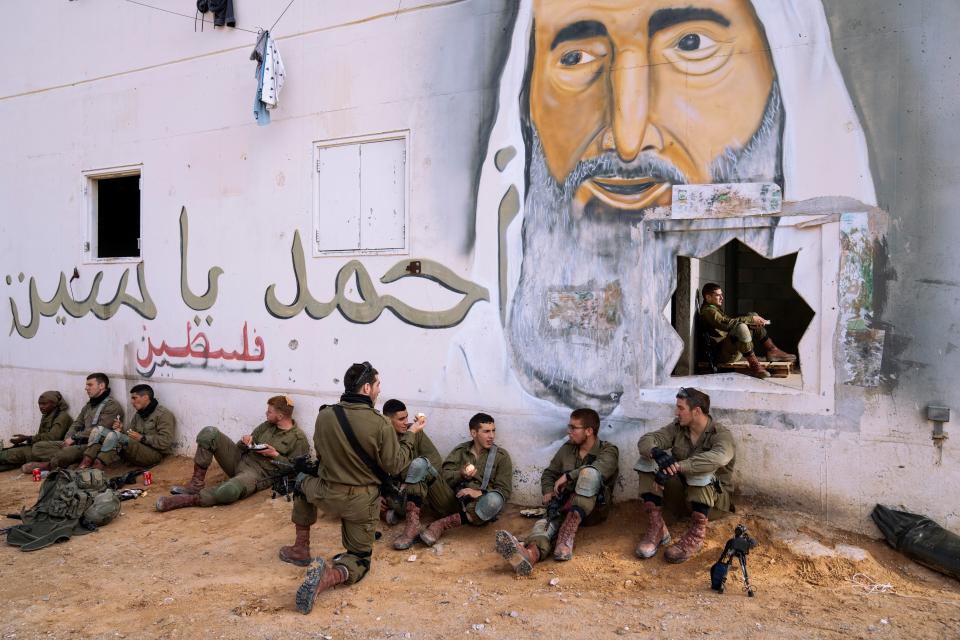 Israeli soldiers rest next to a mural depicting the late Hamas leader Sheikh Ahmad Yassin, during an urban warfare exercise at an army training facility, in Zeelim army base, southern Israel, Jan. 4, 2022.