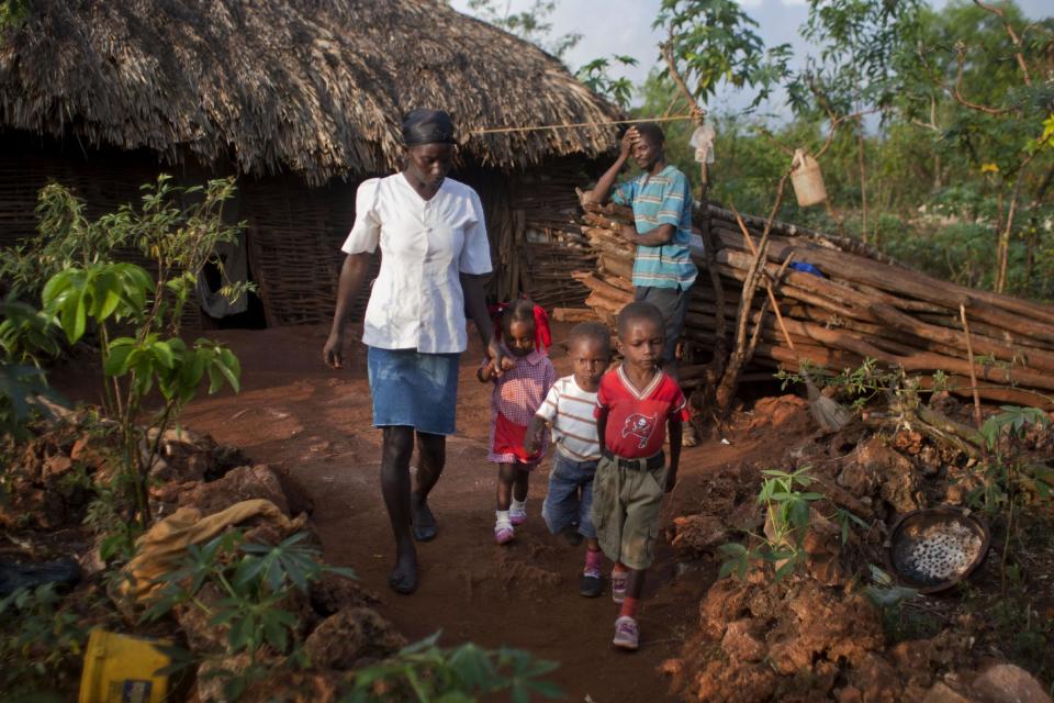 In this Wednesday, March 26, 2014 photo, Jeanilia Jean-Baptiste, 38, left, walks her children to pre-school in Bombardopolis, Haiti. Bombardopolis is relatively fortunate in its misery. It sits atop a plateau called “The Platform” that overlooks the Caribbean, and it still has some healthy-looking trees. But the drought puts those too at risk. (AP Photo/Dieu Nalio Chery)