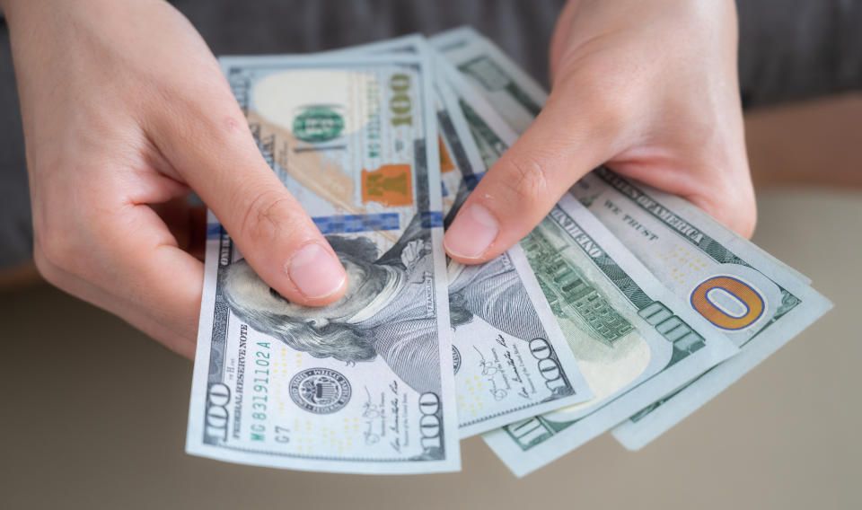 woman holding a stack of hundred dollar bills like a fan