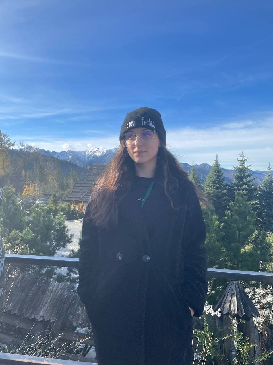 A photo of Solomiya standing on a balcony against a backdrop of a wooded area