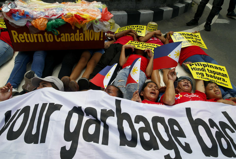 Environmentalists stage a mock die-in protest outside the Canadian Embassy to demand the Canadian government to speed up the removal of several containers of garbage that were shipped to the country Tuesday, May 21, 2019, in Manila, Philippines. The Philippines recalled its ambassador and consuls in Canada last week over Ottawa's failure to comply with a deadline to take back 69 containers of garbage that Filipino officials say were illegally shipped to the Philippines years ago. (AP Photo/Bullit Marquez)