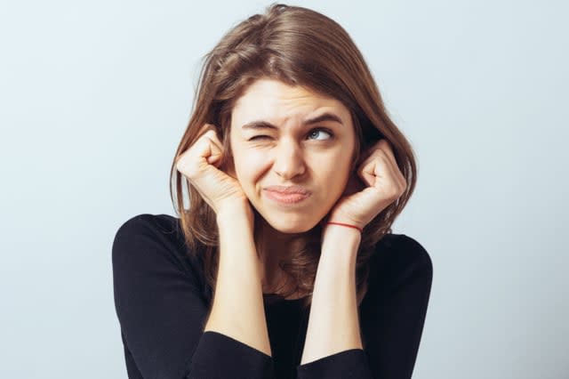 long-haired beautiful young brunette woman covering her ears with her hands, isolated on a white background; Shutterstock ID 280