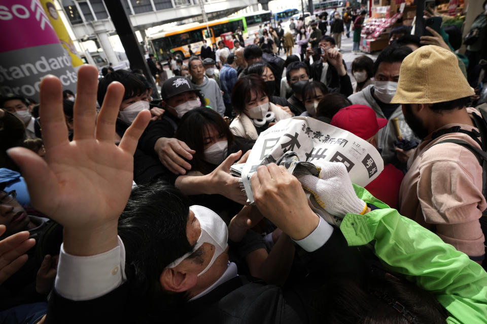 An employee distributes extra editions of the Yomiuri Shimbun newspaper reporting on Japan's victory at the final match of the World Baseball Classic Wednesday, March 22, 2023, in Tokyo. The headline of the newspaper said "Japan is No. 1 in the World." (AP Photo/Eugene Hoshiko)