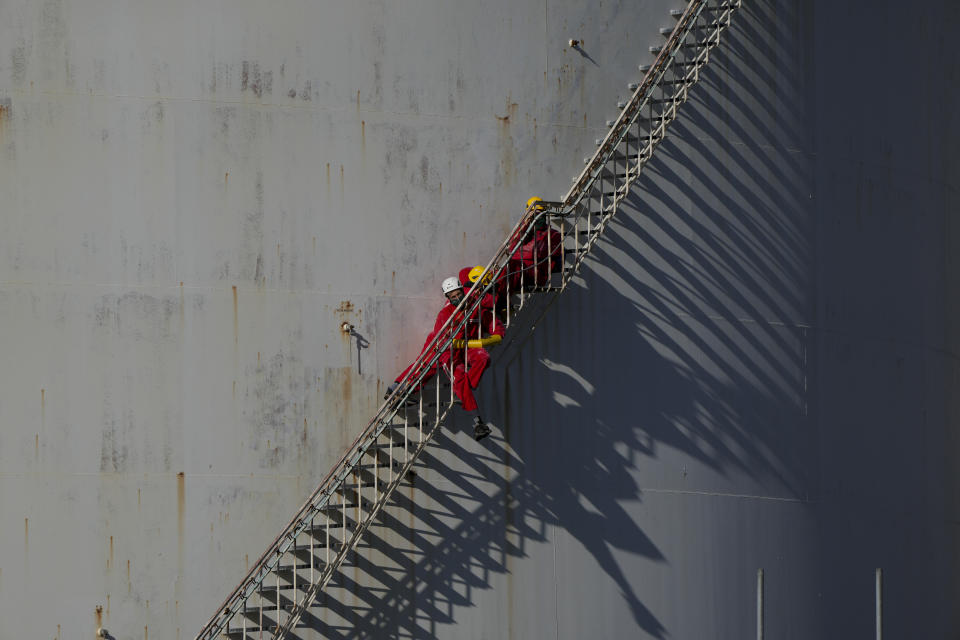 Greenpeace climate activists block the access on the staircase of a fuel storage tank as others stage a protest at a Shell refinery in Rotterdam, Netherlands, Monday, Oct. 4, 2021. A coalition of environmental groups launched a campaign calling for a Europe-wide ban on fossil fuel advertising ahead of the United Nations Climate Change Conference, also known as COP26, which start in Glasgow on Oct. 31st, 2021. (AP Photo/Peter Dejong)