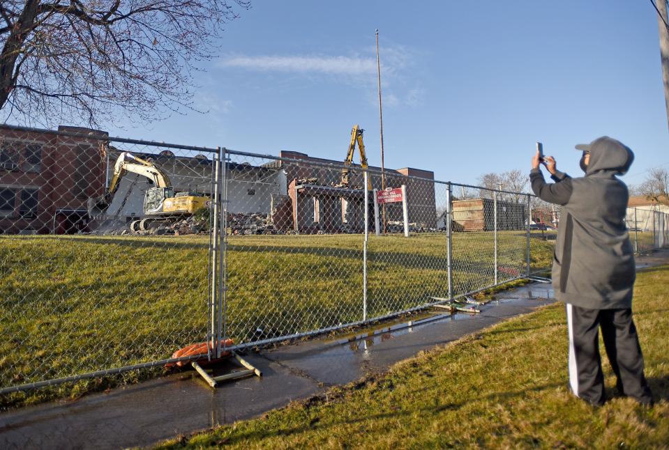 Jackie Rawls uses her phone to record the demolition of the Ocie Hill Neighborhood Center on Wednesday morning. Rawls was a student in the building from kindergarten until 6th grade when it was known as Creveling School.