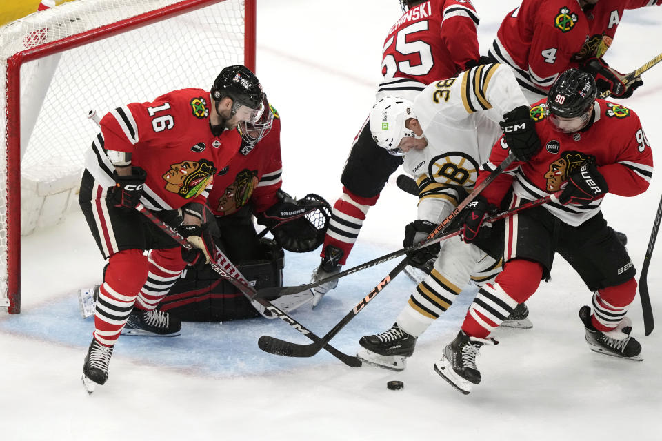 Chicago Blackhawks' Jason Dickinson (16) and Tyler Johnson (90) keep Boston Bruins' Patrick Brown from getting a shot on goal during the second period of an NHL hockey game Tuesday, Oct. 24, 2023, in Chicago. (AP Photo/Charles Rex Arbogast)