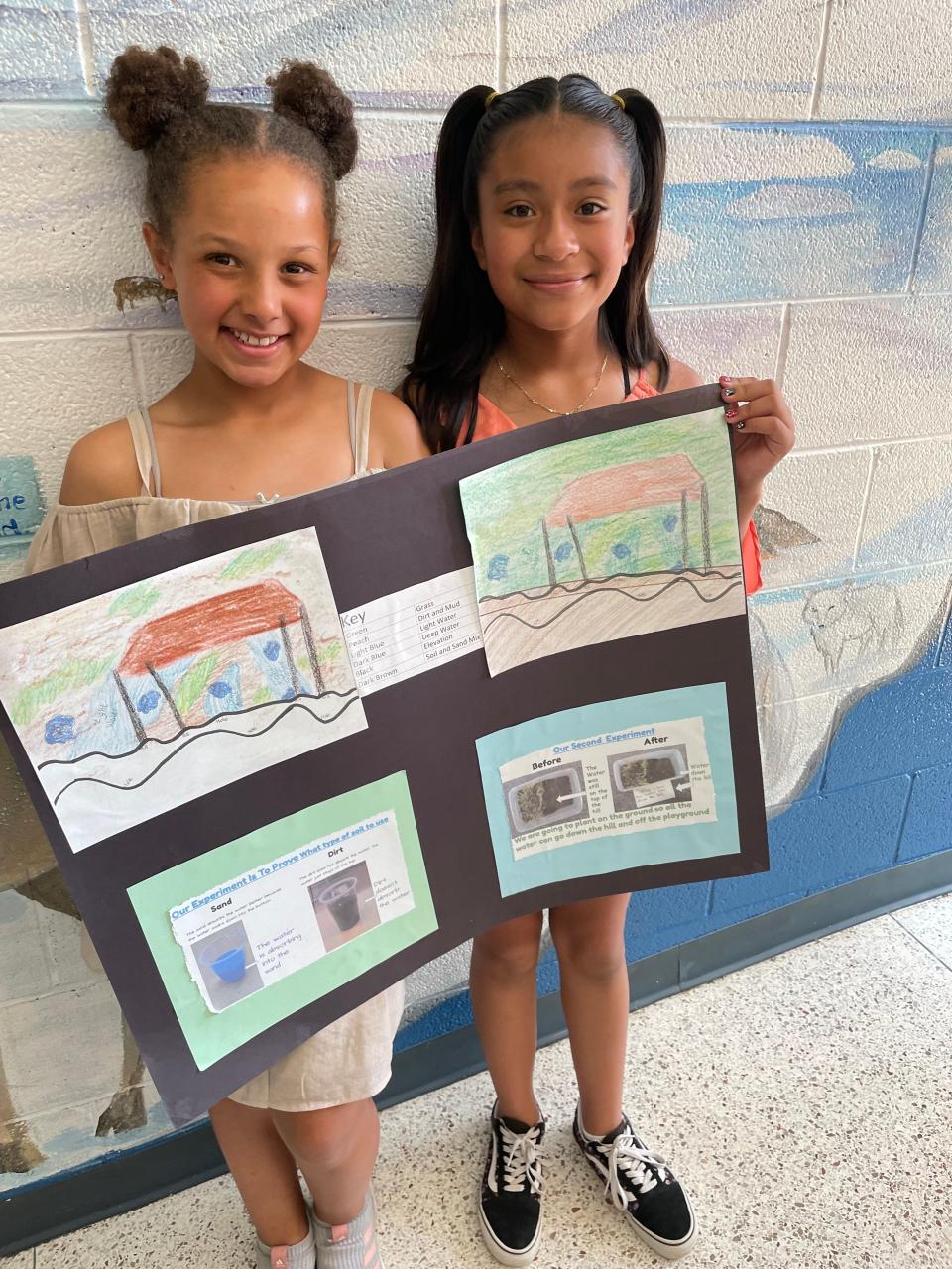 Noeleigh Wells (left) and Alisson Rosas Leal hold a poster that is part of their award-winning project. May 2022