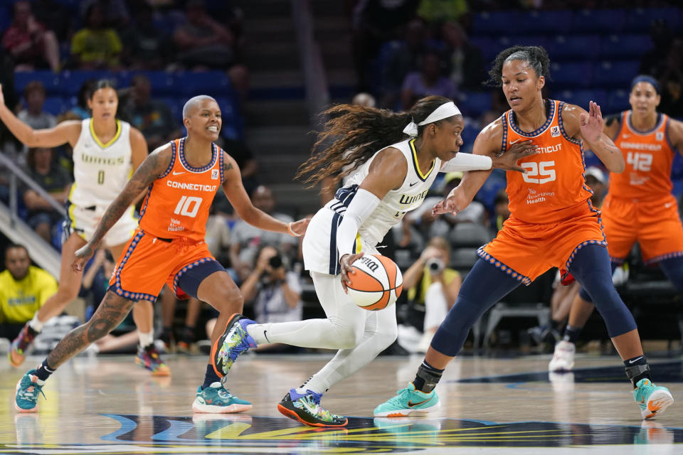 Dallas Wings guard Arike Ogunbowale, center, drives against Connecticut Sun guard Courtney Williams (10) and forward Alyssa Thomas (25) during the first half of a WNBA basketball game in Arlington, Texas, Tuesday, July 5, 2022. (AP Photo/LM Otero)