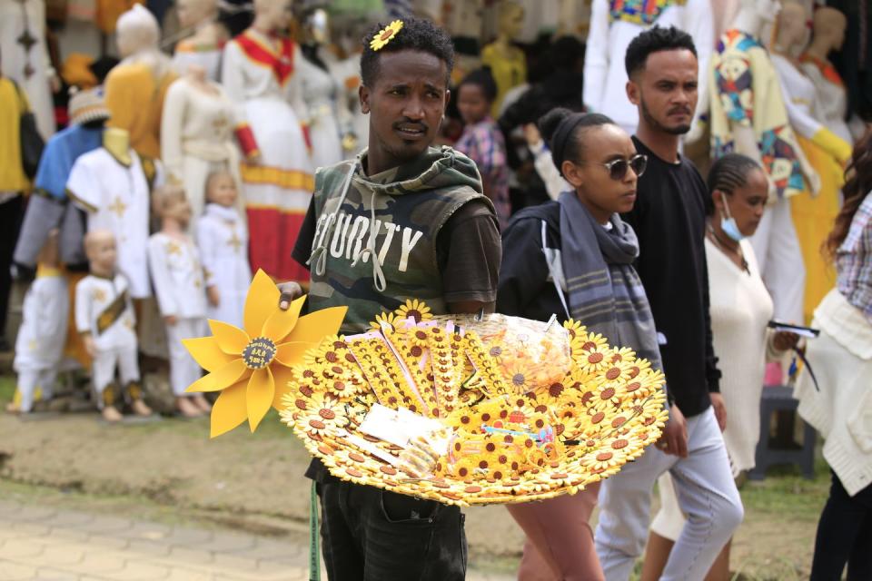 new year preparations in addis ababa ethiopian new year enkutatash, image of young man holding tray of yellow paper daisies for sale ahead of enkutatash celebrations